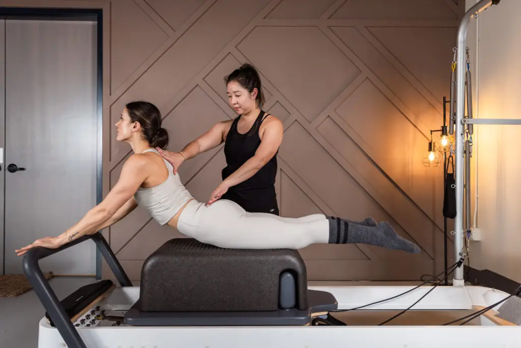 reformer pilates instructor assist client